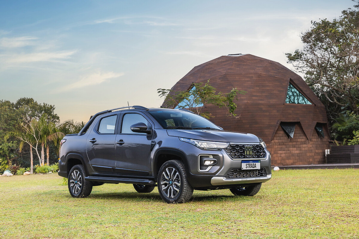 A picape Fiat Strada 2026 (Willys 4x4) correndo em primeiro lugar com uma vantagem massiva sobre o pelotão desfocado ao fundo, ressaltando sua liderança absoluta no mercado brasileiro de janeiro-fevereiro 2026. Logotipo Motores e AÇÃO integrado.